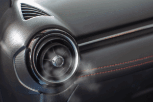 car a/c smells bad. Auto repair shop in Republic, MO. Yocum Automotive. Cold air visibly blowing out of a round car A/C vent on a black dashboard with red stitching detail.