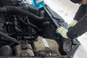 Car Maintenance Checklist. Auto repair shop in Republic, MO. Yocum Automotive. A mechanic working on a car's engine under the hood in snowy conditions, emphasizing cold-weather car maintenance.